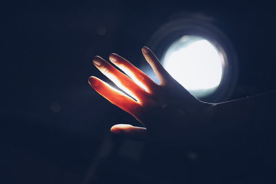 Close-up of illuminated hand against sky