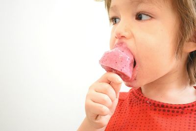 Close-up of girl eating ice cream against white background