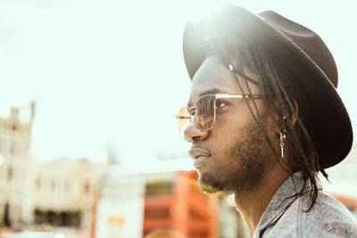 Close-up of young man standing in city against sky