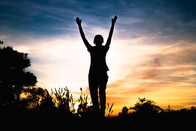 Silhouette man standing by plants against sky during sunset