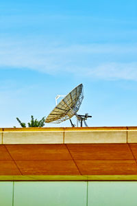 Low angle view of telephone on roof against sky
