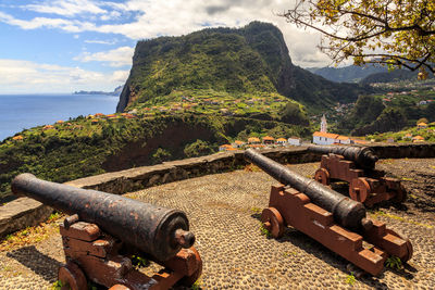 Scenic view of sea by mountain against sky