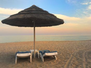 Lounge chairs on beach  against sky during sunset, beach