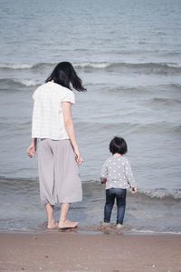 Rear view of women standing on beach