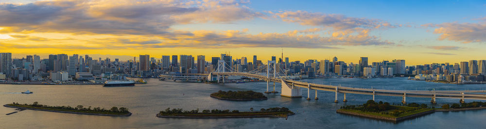 Panoramic view of river and buildings against sky during sunset