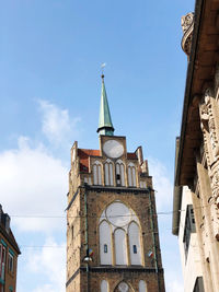 Low angle view of clock tower amidst buildings against sky