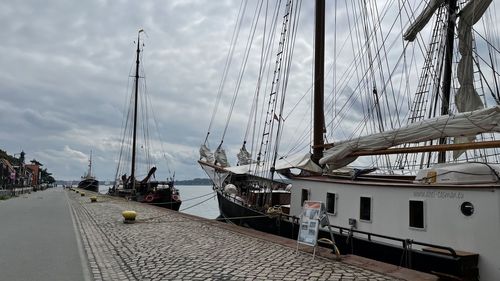 Sailboats moored at harbor against sky