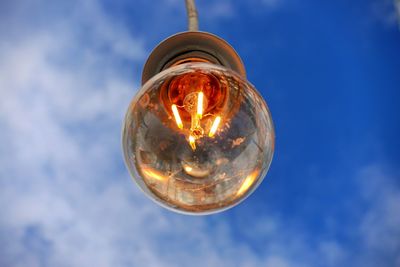 Low angle view of illuminated light bulb against sky