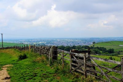 Scenic view of land against sky with city in distance