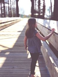 Rear view of woman standing on wood