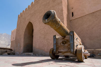 Old medieval cannon by a weathered building against clear sky