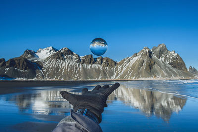 Person hand against clear blue sky