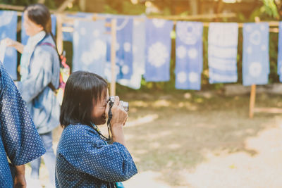 Rear view of girl photographing outdoors