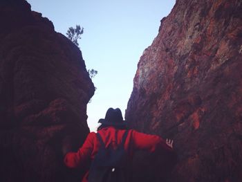 Rear view of man on rock against sky