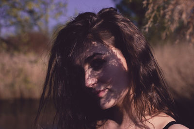 Close-up portrait of woman with shadow on face against plants