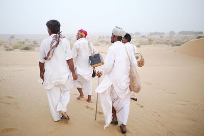 Rear view of people walking on beach