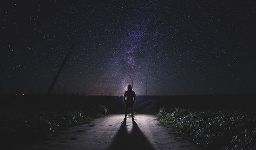 Rear view of silhouette man standing against star field at night