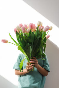 A little boy holds a tender bouquet of pink and white tulips.