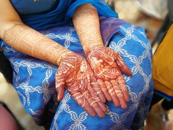 Midsection of woman with henna tattoo on hand