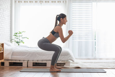 Full length side view of woman exercising at home