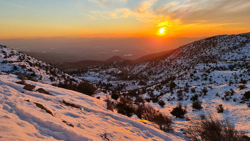 Aerial view of snowcapped mountains against sky during sunset
