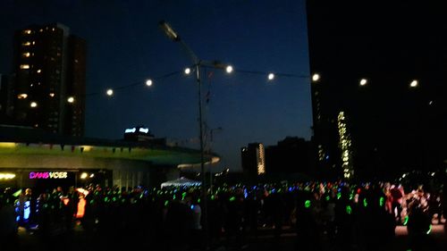 Crowd on illuminated city against sky at night