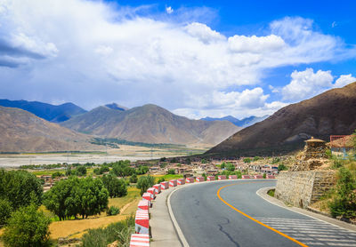 Scenic view of road and mountains against cloudy sky