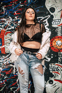 Portrait of woman standing against graffiti wall