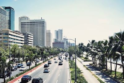 Vehicles on road amidst buildings in city against sky