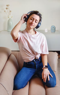 Young woman listening music while sitting on sofa at home