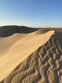 Sand dunes in desert against clear sky