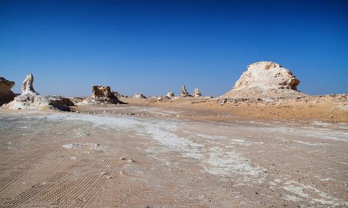 Rock formations on beach against clear blue sky