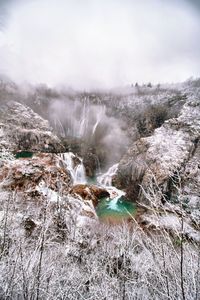 Scenic view of waterfall against sky during winter