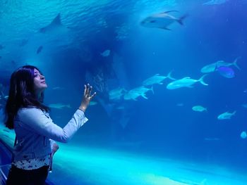 Young woman standing in aquarium