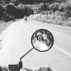 Reflection of woman photographing while sitting on motorcycle