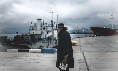 Man standing at harbor against sky