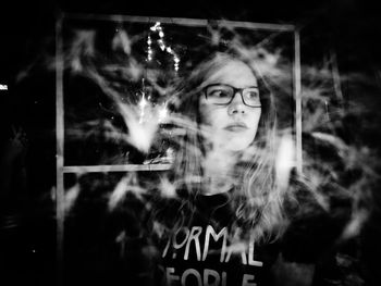 Portrait of young woman with text against window at night