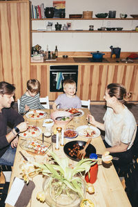 High angle view of happy family having fun while having dinner at dining table in kitchen