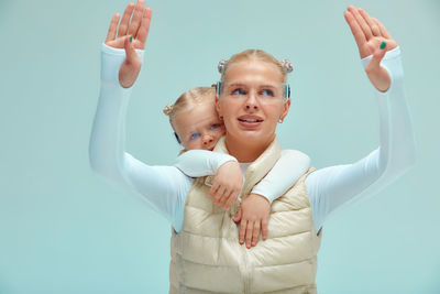 Portrait of smiling young woman with arms raised standing against white background