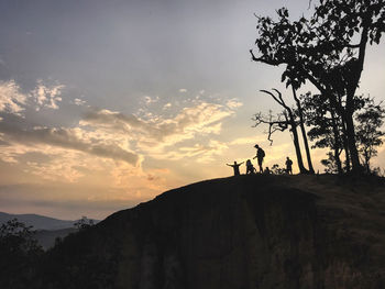 Silhouette people standing on mountain against sky during sunset