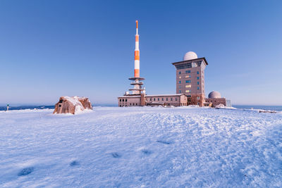 Lighthouse on snow covered building against clear sky