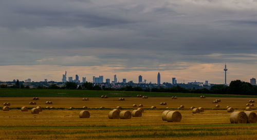 Hay bales on field against sky during sunset