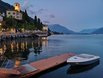 Illuminated town by sea during sunset