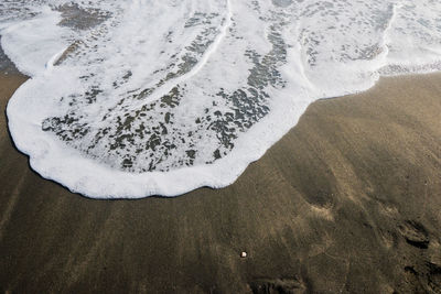 Beautiful soft wave on black sand at the sea, sunny day.