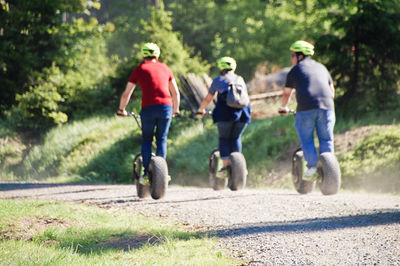 Rear view of people riding scooter on road