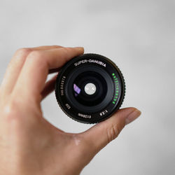 Close-up of hand holding camera against white background