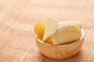 Close-up of potato chips in wooden bowl on burlap