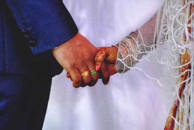 Midsection of wedding couple holding hands