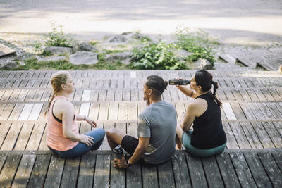 High angle view of male and female friends sitting on steps during break after work out