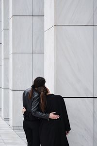 Rear view of woman standing against wall